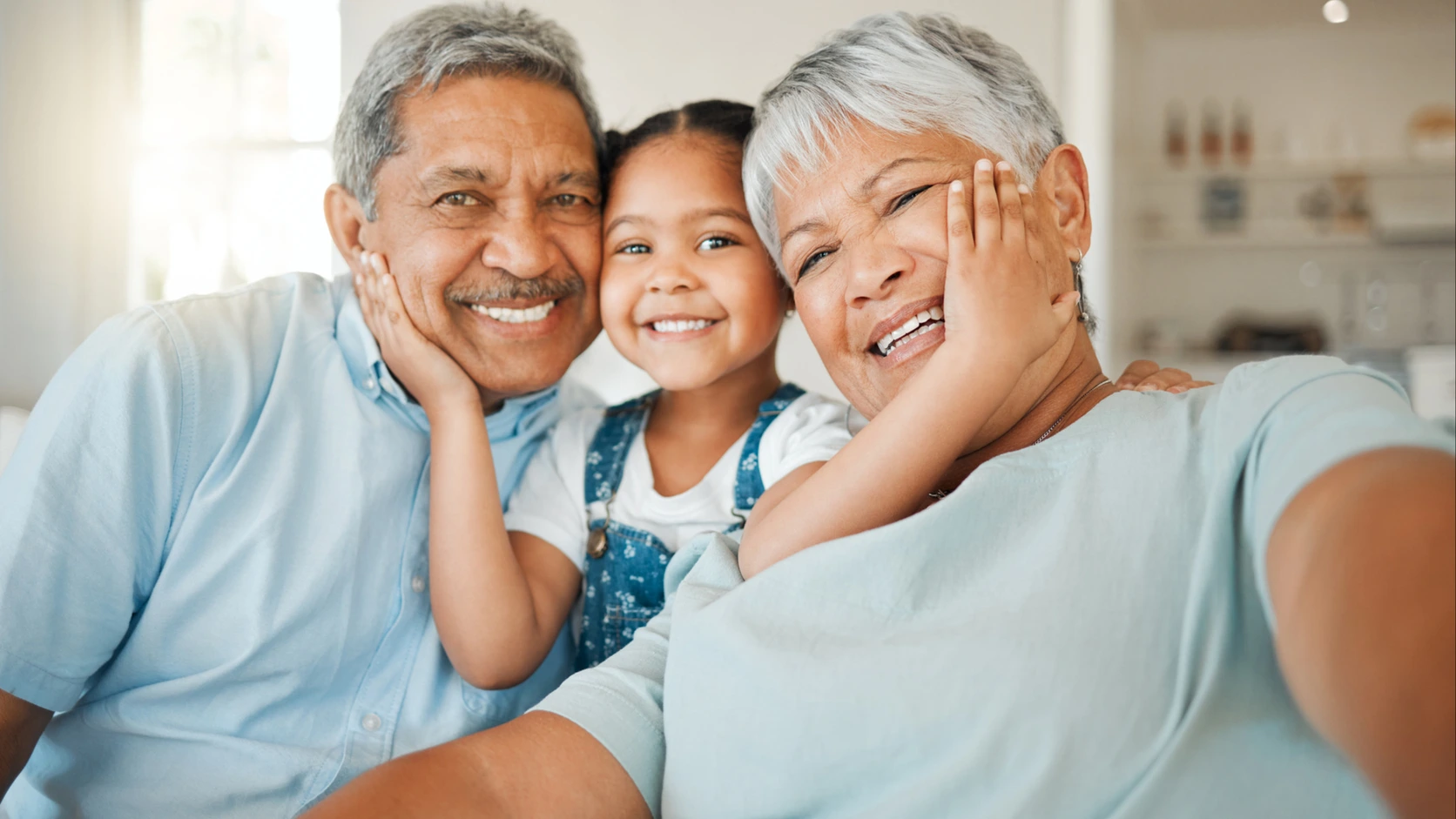 Abuelos sonriendo junto a su nieta en la sala de casa