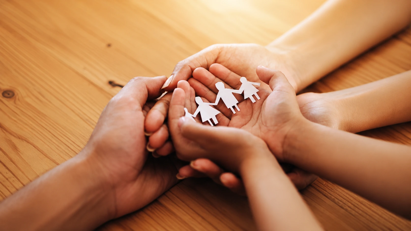 Manos de una familia sosteniendo juntas una figura de papel de padres e hijos