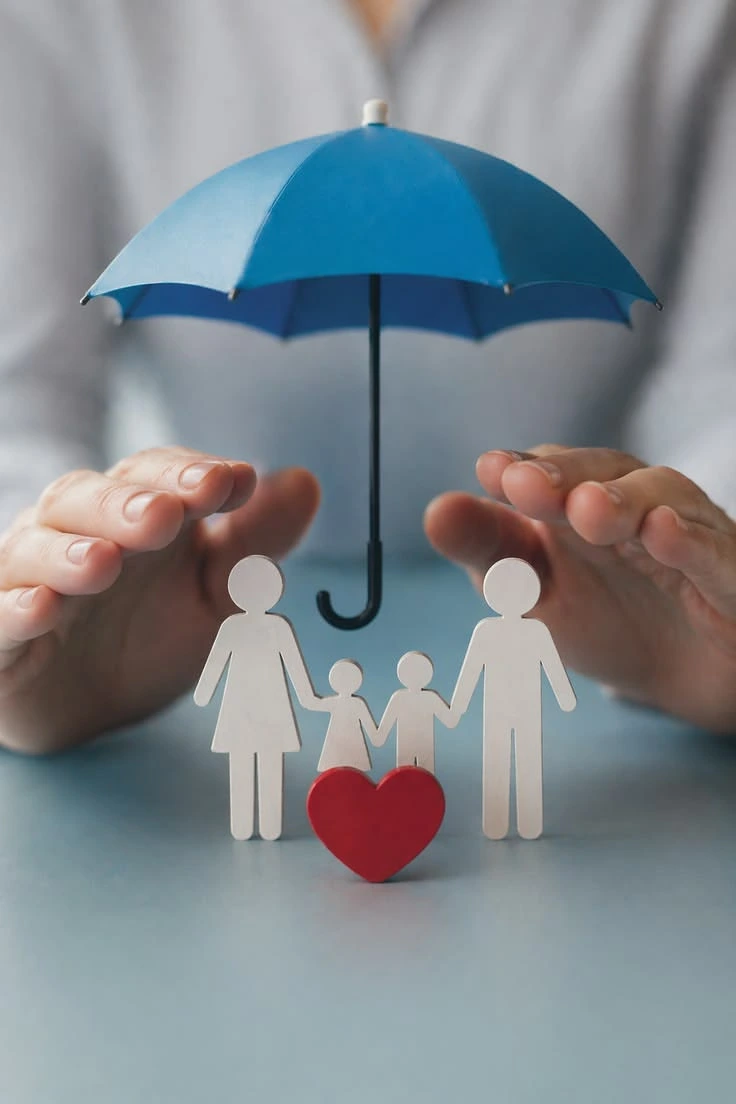 Manos protegiendo con una sombrilla a una familia de papel junto a un corazón — seguro de vida